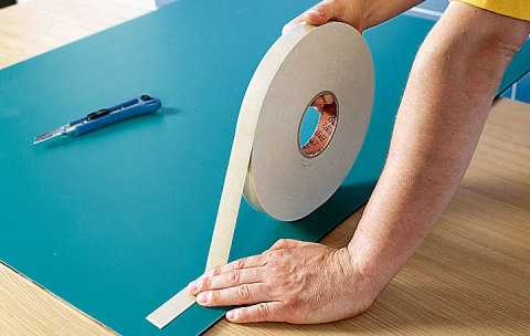 Vemos o processo de colar fita dupla face no espelho.