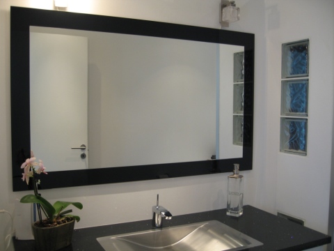 Vemos um espelho na moldura na parede.